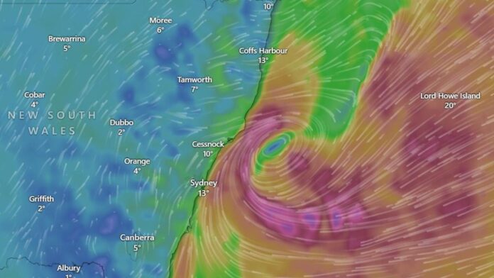 Citra radar cuaca menunjukkan pusat bomb cyclone berputar di lepas pantai Sydney dengan pola angin rapat berwarna ungu – merah.