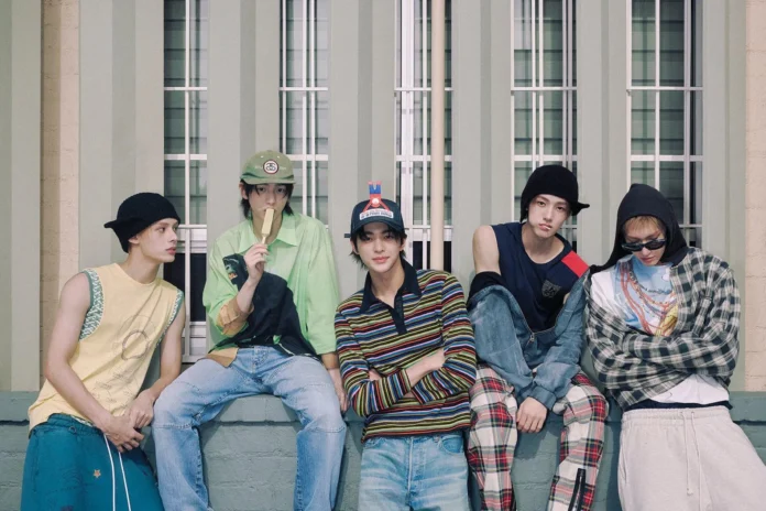 Foto editorial bertema CORTIS—boy group baru HYBE—menampilkan lima remaja bergaya streetwear duduk di depan fasad jendela bernuansa hijau.