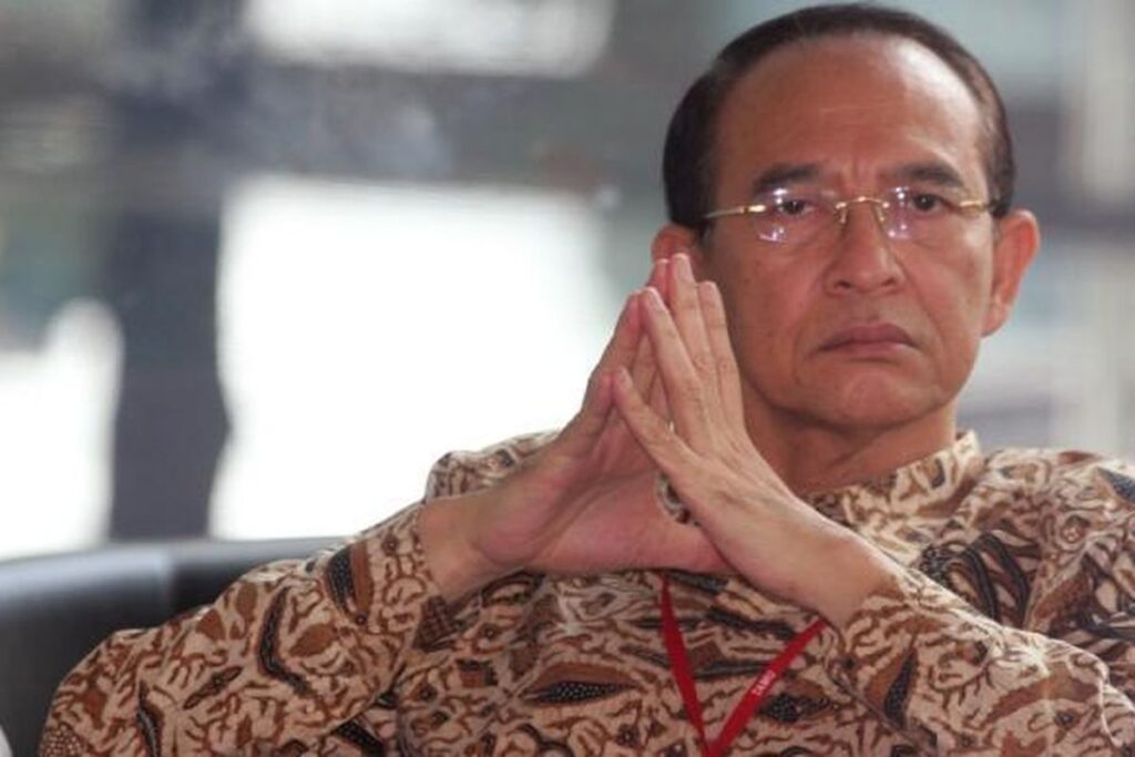 Mantan Menteri Agama Suryadharma Ali mengenakan kemeja batik dan kacamata, duduk dengan tangan menyatu.