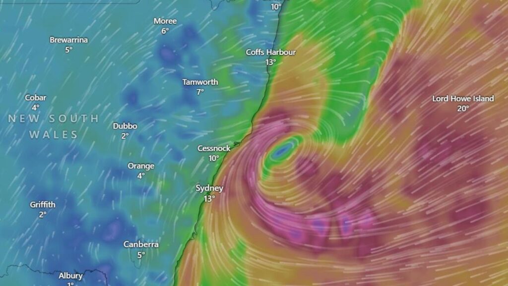 Citra radar cuaca menunjukkan pusat bomb cyclone berputar di lepas pantai Sydney dengan pola angin rapat berwarna ungu – merah.