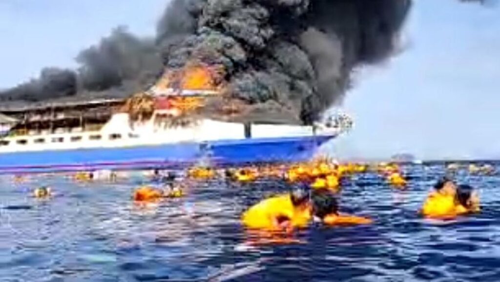 Penumpang berpelampung mengapung di laut sementara kapal terbakar KM Barcelona V memuntahkan asap hitam di perairan Pulau Talise, Sulawesi Utara.