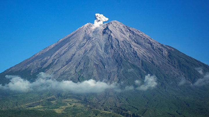 Gunung Semeru erupsi, kolom abu membumbung di atas puncak Jonggring Saloka dengan langit cerah